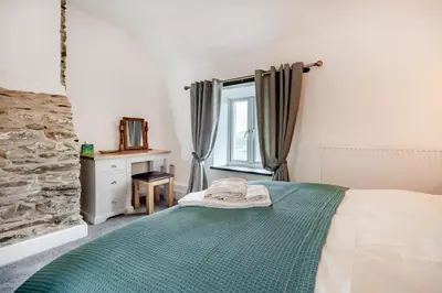 a bedroom with a bed with a green blanket and a window at 3 Bed in Tywyn oc-h32633 in Tywyn