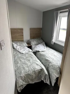a bedroom with two beds and a window at Luxury static caravan on SunnySands with mountain views in Barmouth
