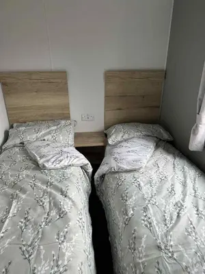 two beds sitting next to each other in a bedroom at Luxury static caravan on SunnySands with mountain views in Barmouth