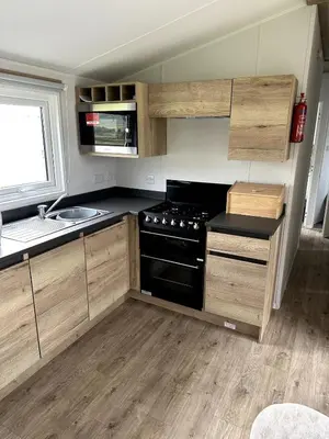 a kitchen with a stove and a sink at Luxury static caravan on SunnySands with mountain views in Barmouth