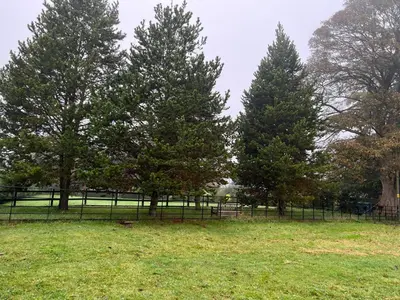 a fence in a field with trees and a park at The Coach House in Church Stretton