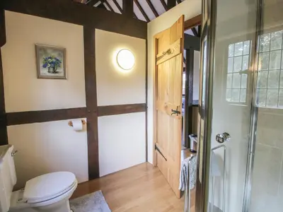 a bathroom with a toilet and a glass door at The Coach House in Church Stretton