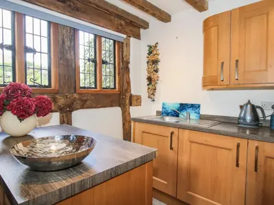 a kitchen with wooden cabinets and a bowl on a counter at Courtyard Cottage in Church Stretton