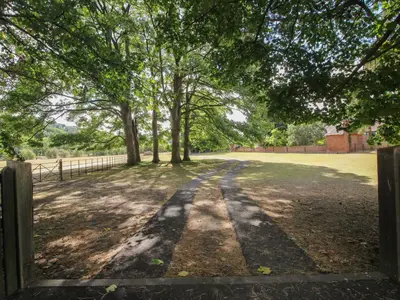 a gate to a field with trees and a fence at Courtyard Cottage in Church Stretton