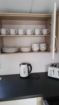 a tea pot on a kitchen counter with plates and cups at T&J Seaview at Pengarreg in Llanrhystyd