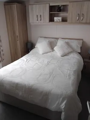 a bed with white sheets and pillows in a bedroom at T&J Seaview at Pengarreg in Llanrhystyd
