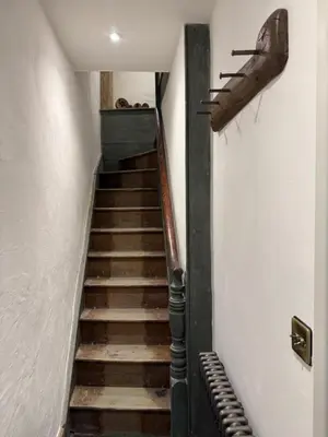 a staircase in a building with a weapon hanging on the wall at Fishermans Cottage at The Old Library in Aberystwyth