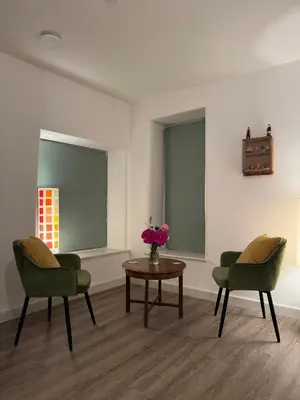 a room with two chairs and a table with a vase of flowers at Fishermans Cottage at The Old Library in Aberystwyth