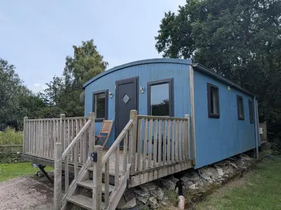 a blue tiny house with a wooden porch at Tranquil Cabin Retreat- Sleeps 2 Parking in Welshpool
