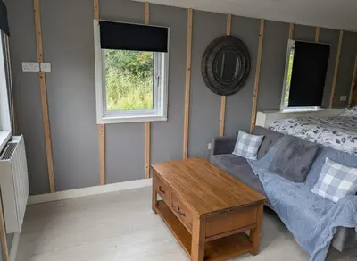a room with a couch and a table and a window at Tranquil Cabin Retreat- Sleeps 2 Parking in Welshpool