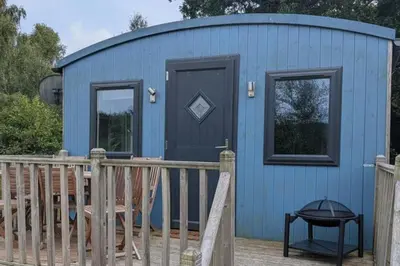 a blue shed with a black door and a fence at Tranquil Cabin Retreat- Sleeps 2 Parking in Welshpool