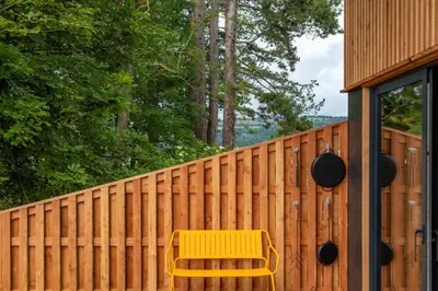 a yellow bench sitting next to a fence at Brackenfell Lodge in Hay-on-Wye