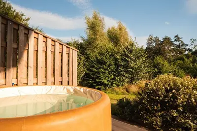 a hot tub in a yard next to a fence at Brackenfell Lodge in Hay-on-Wye