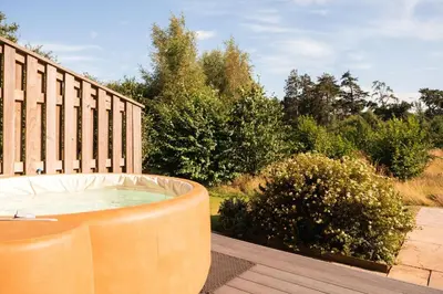 a hot tub sitting on a deck next to a fence at Cedar Lodge in Hay-on-Wye