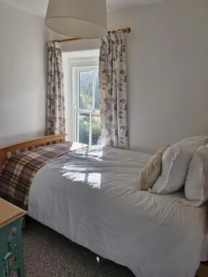 a bedroom with a large bed with a window at Rustic Welsh cottage in Llanwrtyd Wells