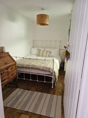 a bedroom with a white bed and a wooden floor at Rustic Welsh cottage in Llanwrtyd Wells