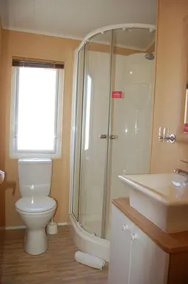 a bathroom with a shower and a toilet and a sink at Morannedd Lodge Barmouth Bay in Llanddwywe
