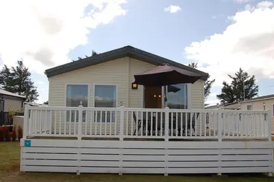 a house with an umbrella on a white fence at Morannedd Lodge Barmouth Bay in Llanddwywe