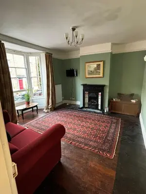 a living room with a red couch and a fireplace at Victorian Town House Shrews in Shrewsbury