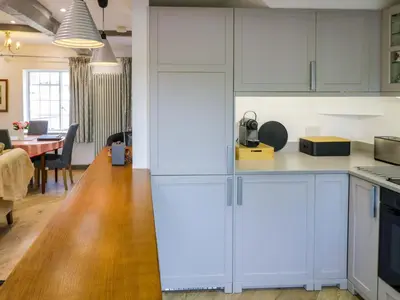 a kitchen with white cabinets and a dining room at Middle Cottage in Ludlow