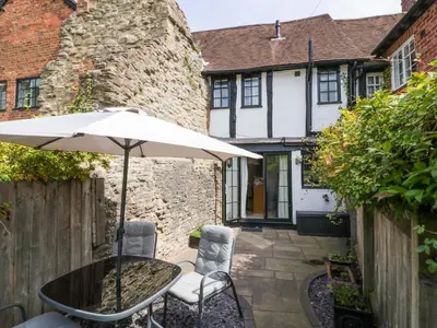 a table and chairs with an umbrella in front of a house at Middle Cottage in Ludlow
