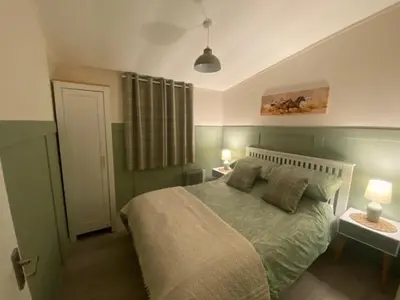 a bedroom with a green bed with two tables and two lamps at Chalet 8 Erw Porthor Happy valley in Tywyn