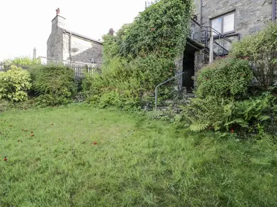 a grassy yard next to a house with a building at Old Post Office in Maentwrog