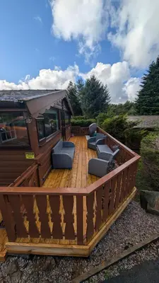 a large wooden deck with chairs on it at IVY Cabin in Trawsfynydd