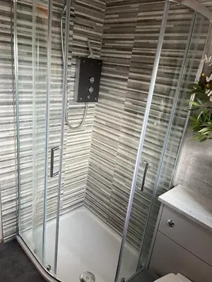 a shower with glass doors in a bathroom at Log Cabin Retreat Snowdonia in Trawsfynydd