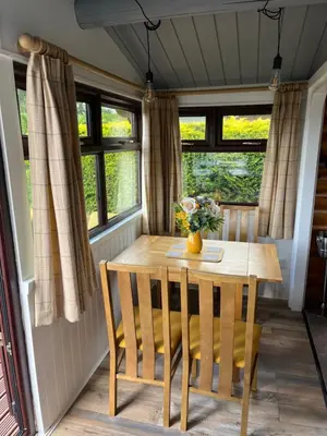 a table and chairs in a room with windows at Log Cabin Retreat Snowdonia in Trawsfynydd