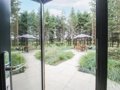 an open door to a patio with tables and umbrellas at The Barn in Bishops Castle