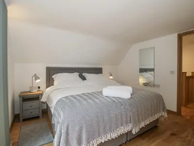a bedroom with a large bed with white sheets at The Barn in Bishops Castle