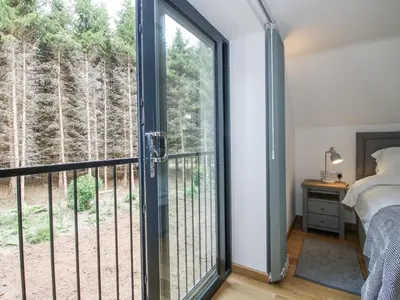 a bedroom with a sliding glass door with a view of the woods at The Barn in Bishops Castle
