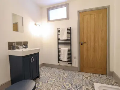 a bathroom with a sink and a mirror and a door at Preesgweene Farmhouse in Oswestry