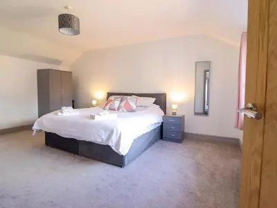 a bedroom with a bed with white sheets and pink pillows at Preesgweene Farmhouse in Oswestry