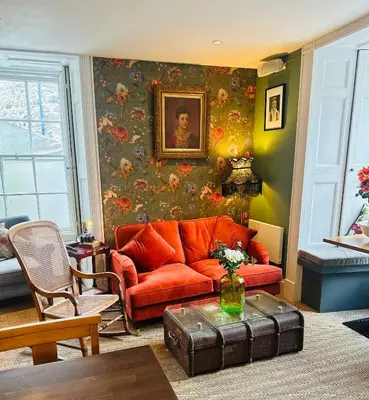 a living room with an orange couch and a painting at Y Meirionnydd Boutique Hotel in Dolgellau