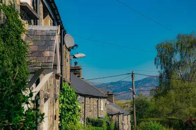 a row of houses with mountains in the background at Little Cott - Cosy Welsh Cottage, a hiking retreat in Maentwrog