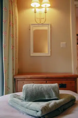 a towel on a bed with a mirror on the wall at Little Cott - Cosy Welsh Cottage, a hiking retreat in Maentwrog