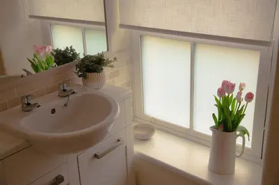 a bathroom with a sink and two windows and flowers at Little Cott - Cosy Welsh Cottage, a hiking retreat in Maentwrog