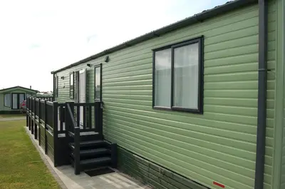 a green house with stairs on the side of it at Premier Caravan 10 at The Vaenol, Tywyn in Tywyn