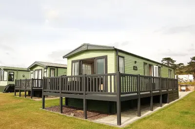 a green house with a porch and a deck at Premier Caravan 10 at The Vaenol, Tywyn in Tywyn