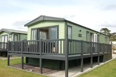 a green holiday home with a porch and a deck at Premier Caravan 10 at The Vaenol, Tywyn in Tywyn