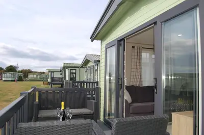 a patio with chairs and a table on a balcony at Premier Caravan 10 at The Vaenol, Tywyn in Tywyn