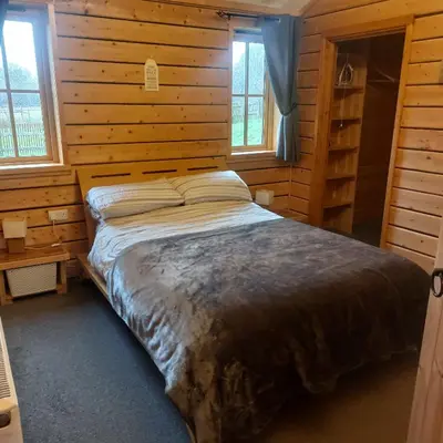 a bedroom with a bed in a wooden cabin at Alpaca cabin-mountain view-hot tub-rural retreat in Llanbrynmair