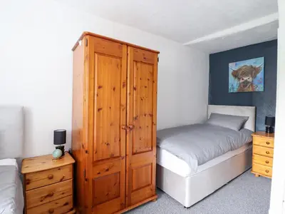 a bedroom with a bed and a wooden cabinet at Plas Yn Bonwm in Corwen