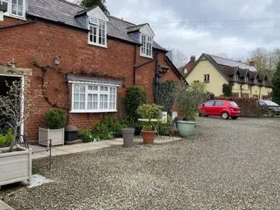a red car parked in front of a brick house at Charming cottage in central Ludlow with parking in Ludlow