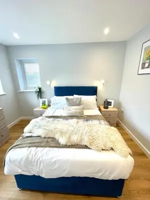 a bedroom with a large bed with a blue headboard at Modern 1 Bed Apartment Sleeps 2 in Llanbadarn-fawr
