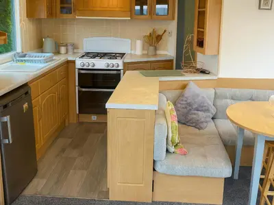 a kitchen with a stove and a couch in it at Brynowen Holiday Park - Holiday Accommodation 19041 in Borth
