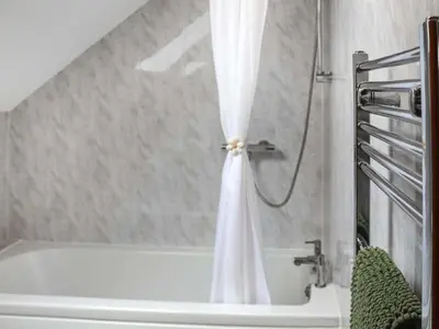 a bathroom with a bath tub with a shower curtain at Cothi Cottage - Uk49588 in Llansawel