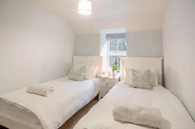 two beds in a white room with a window at Luxury Cottage near Dolgellau in Llanfachreth